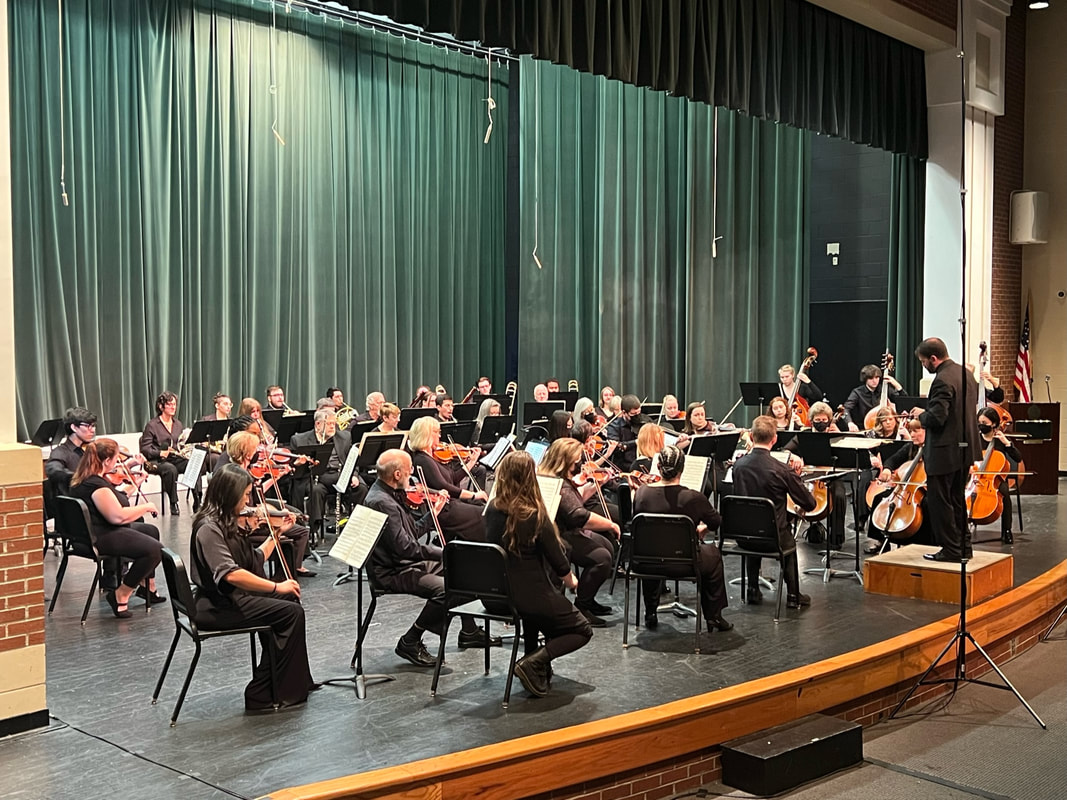 The full orchestra performing on the Bryan Station High School auditorium stage.